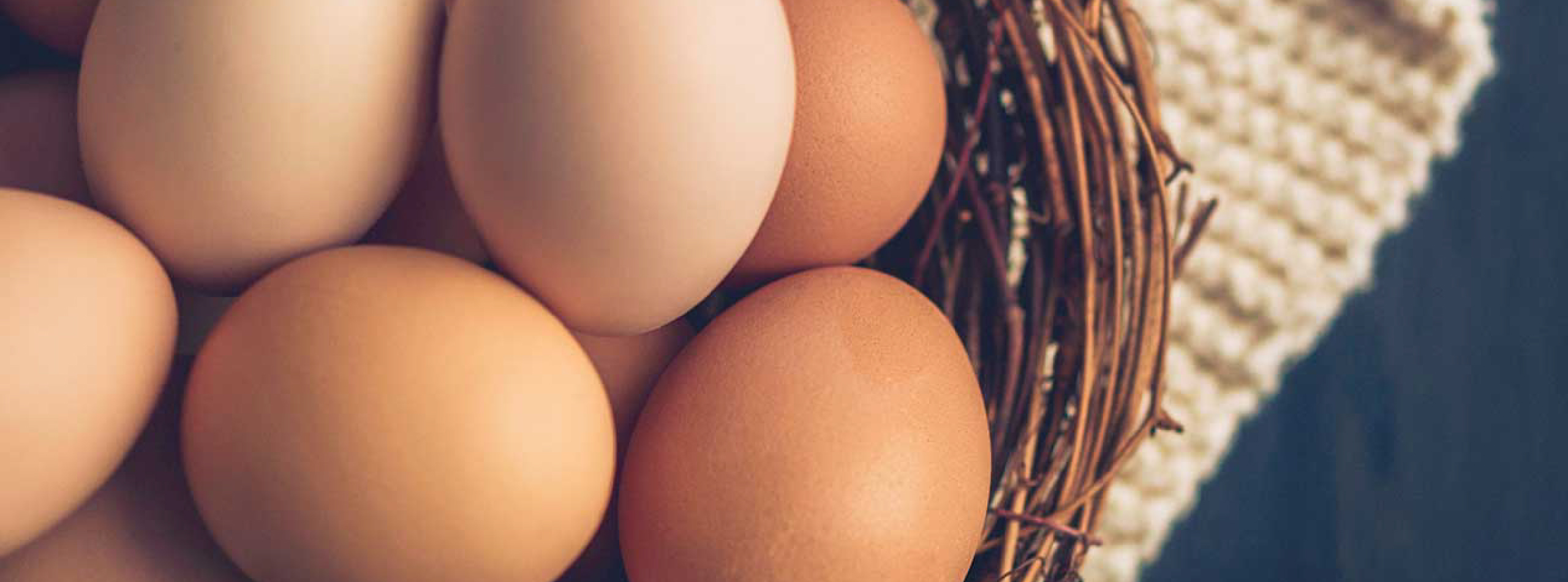 A woven basket containing several eggs resting on a table