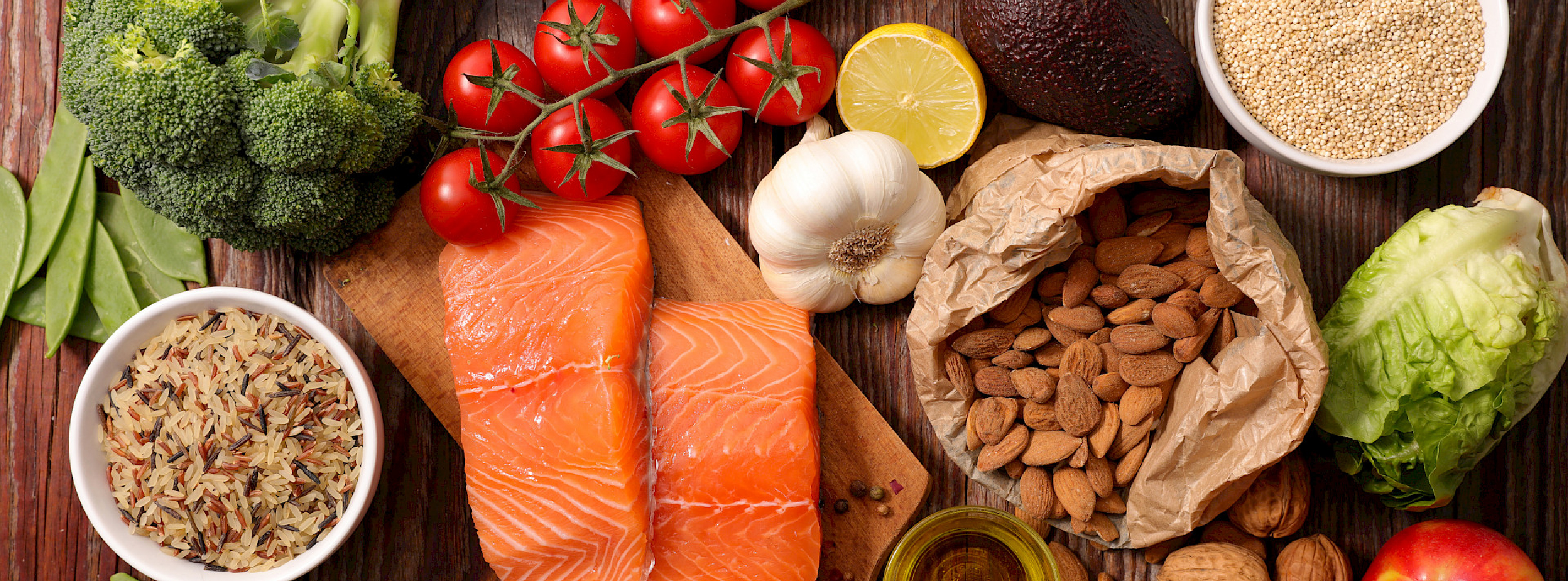 A colourful assortment of foods including salmon, broccoli, almonds, and various other nutritious items on a plate.