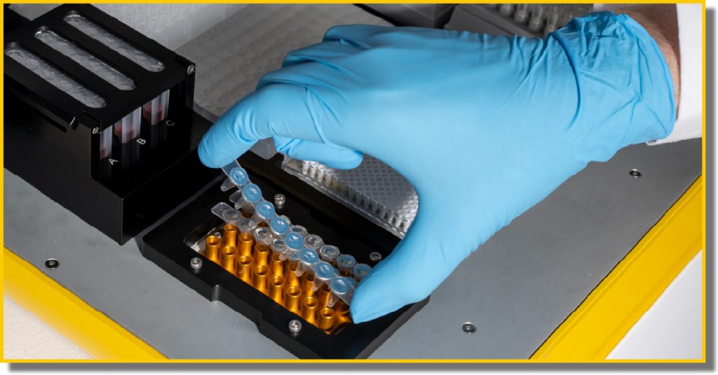 A person in blue gloves holds a small device, focusing intently on its features.