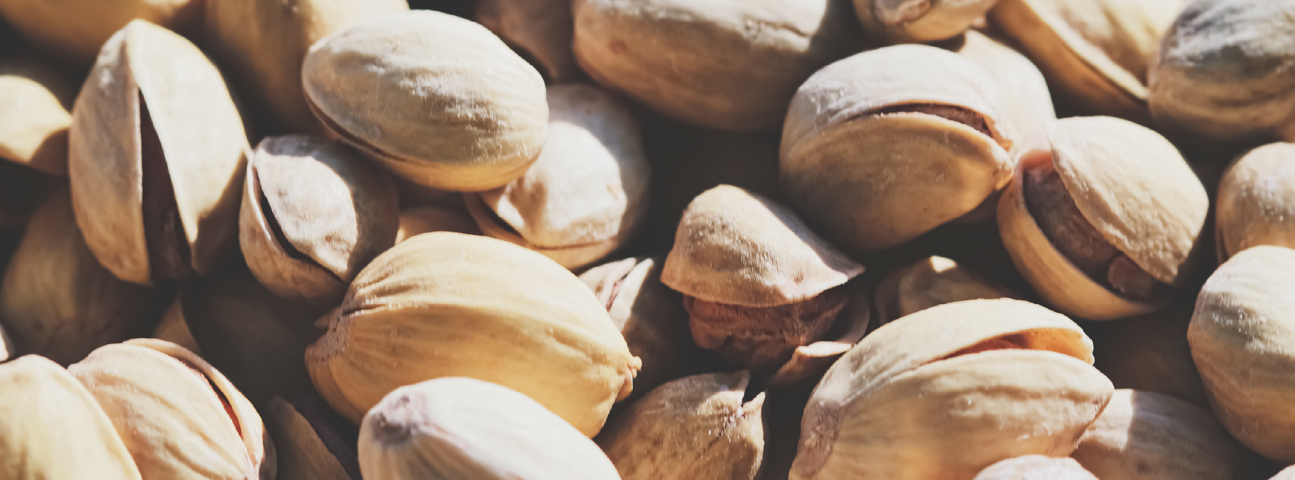 A close-up view of a pile of shelled and unshelled pistachios on a textured surface.