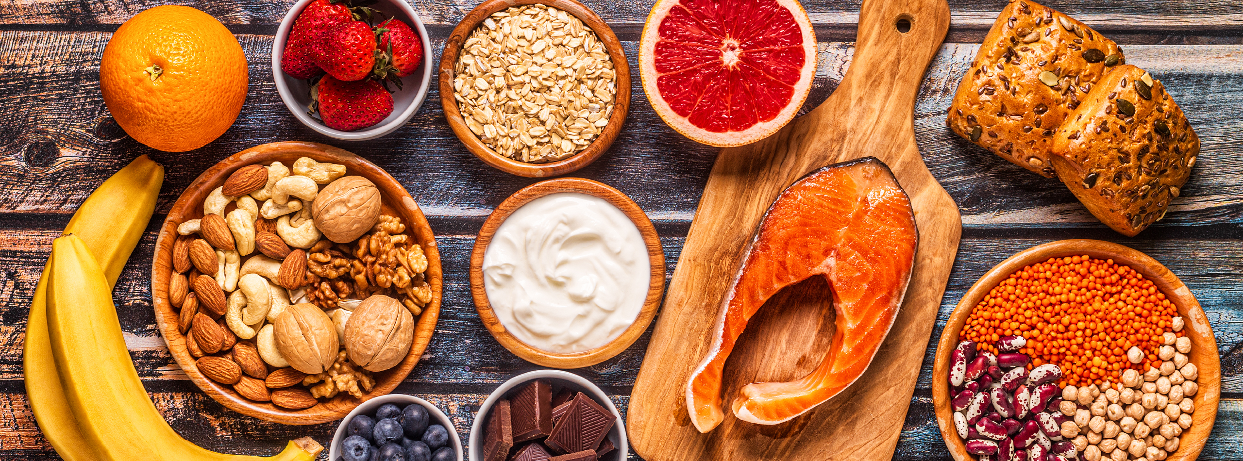 A colourful assortment of nuts, fruits, fish and vegetables displayed together on a wooden surface.