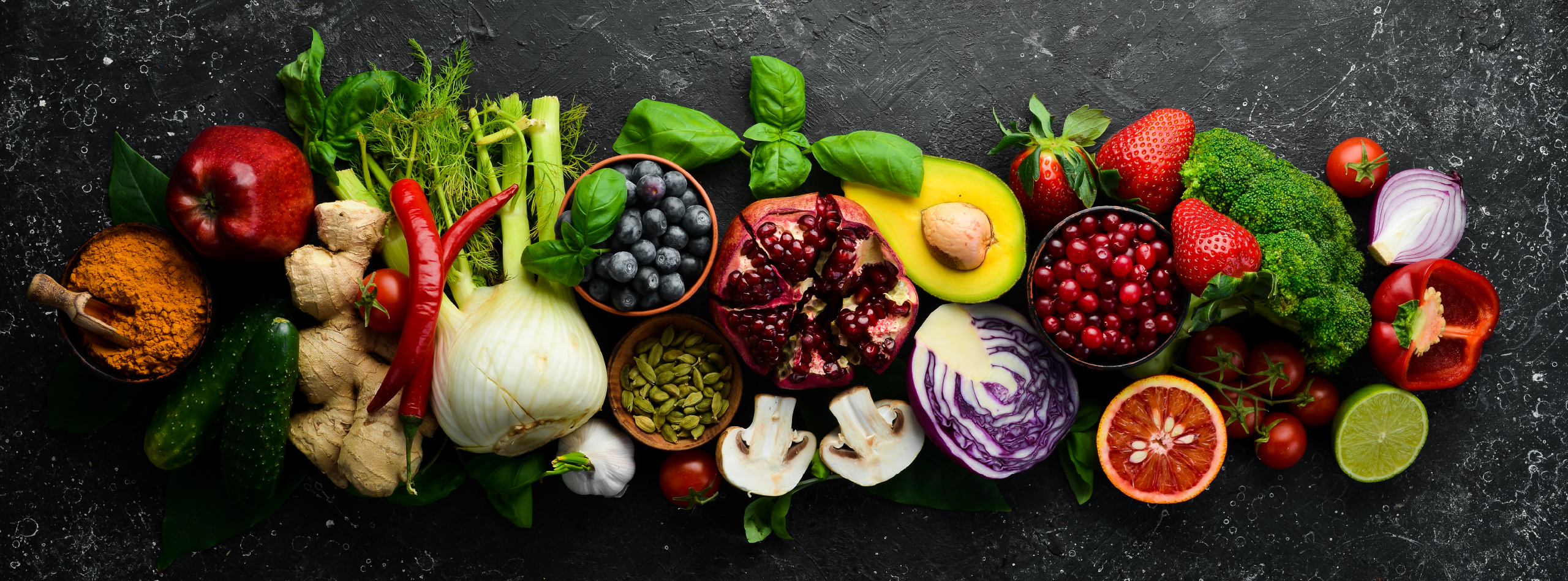 A colourful assortment of fruits and vegetables arranged in a line on a black board