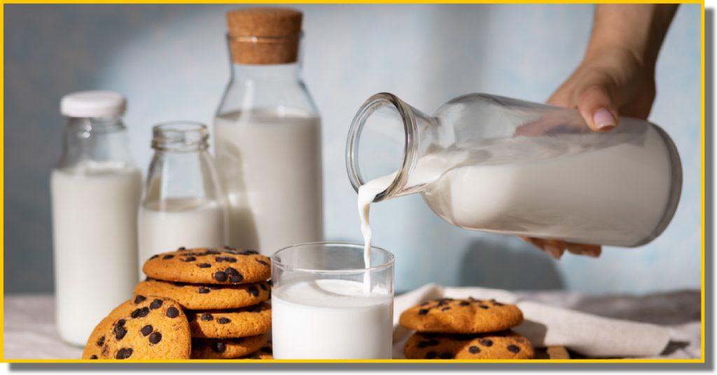 A person pours milk into a glass beside a plate of cookies on a table.
