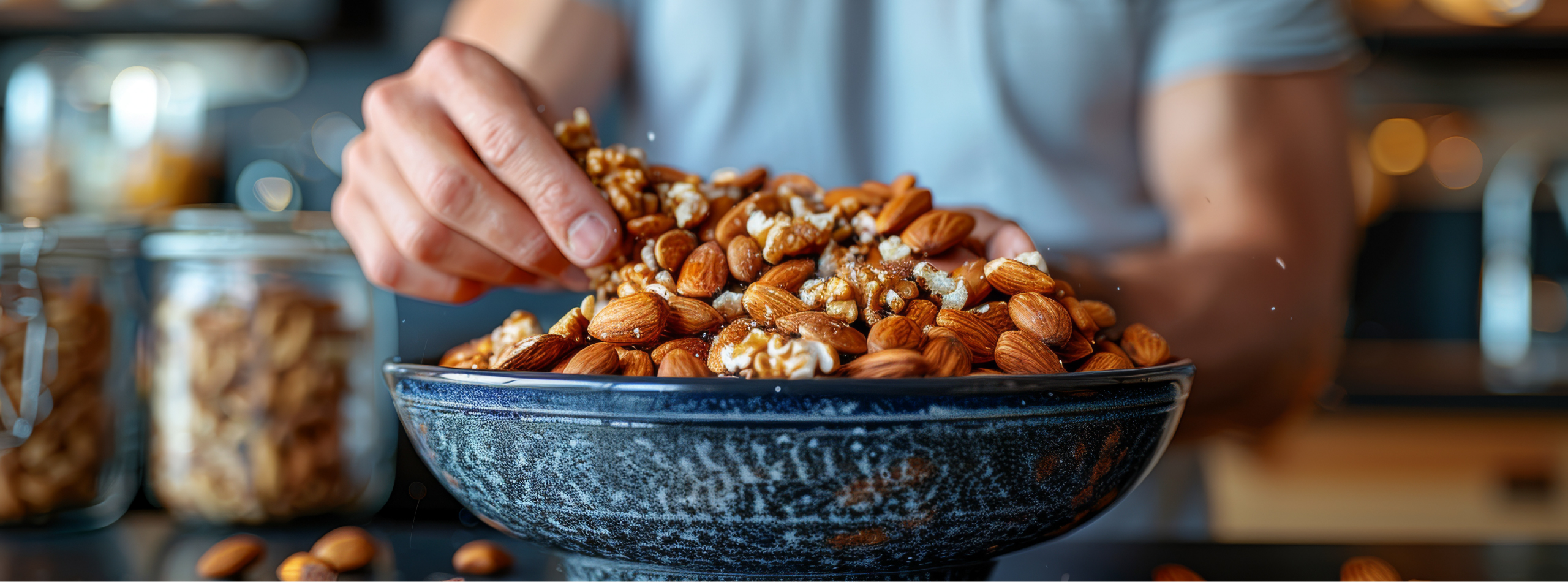 A person holds a bowl filled with various nuts, showcasing a mix of almonds, walnuts, and cashews