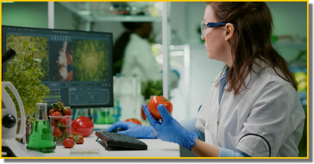 A woman in a lab coat is focused on her work while using a computer in a laboratory setting.