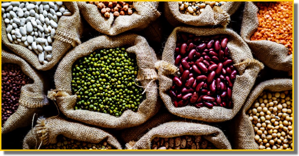 A collection of assorted beans and seeds displayed in hessian bags on a table.