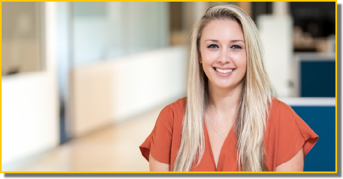 A smiling woman wearing an orange shirt, exuding warmth and positivity.