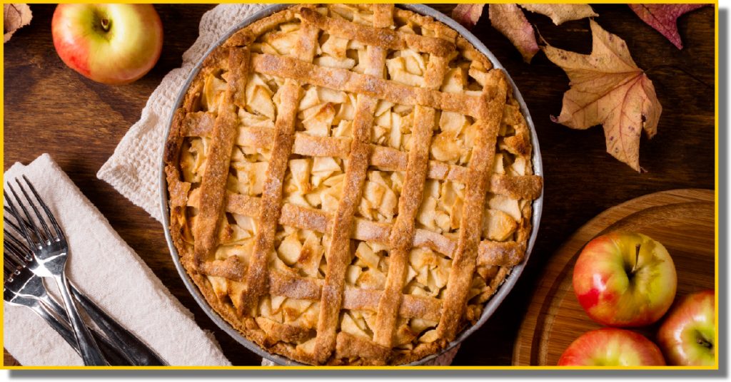 A freshly baked apple pie with a lattice crust sits on a wooden table