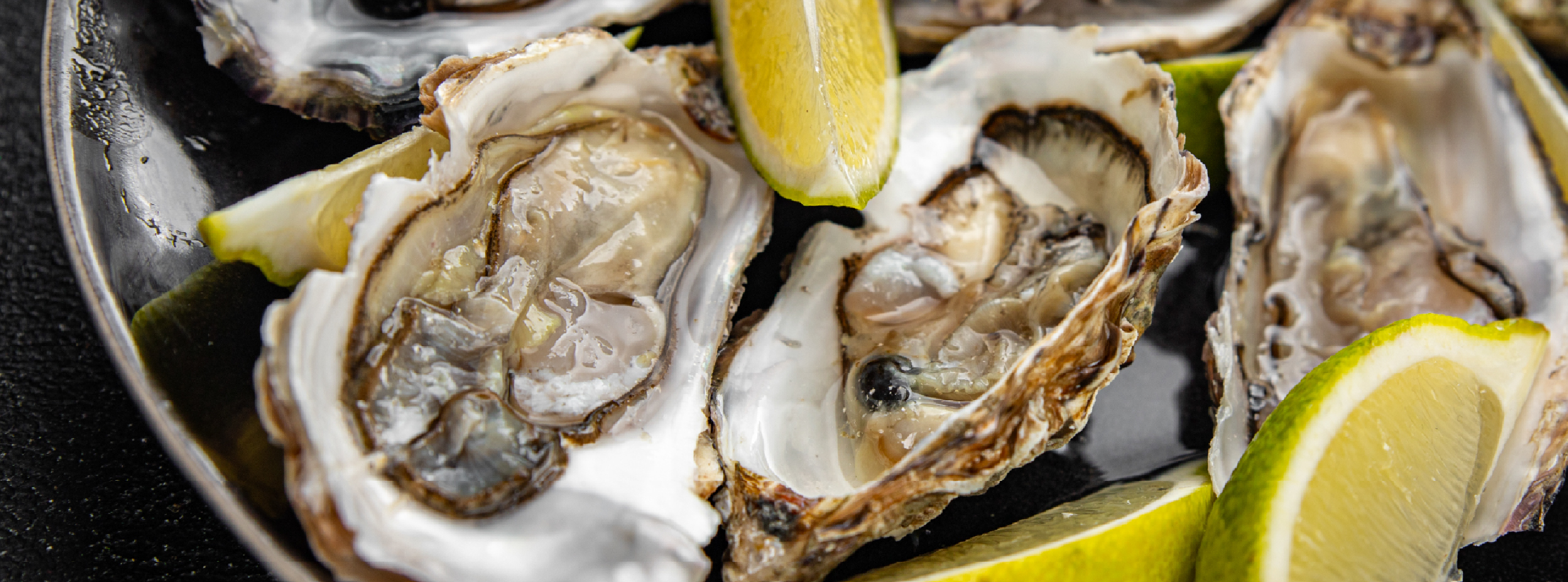 A plate of fresh oysters garnished with lime wedges