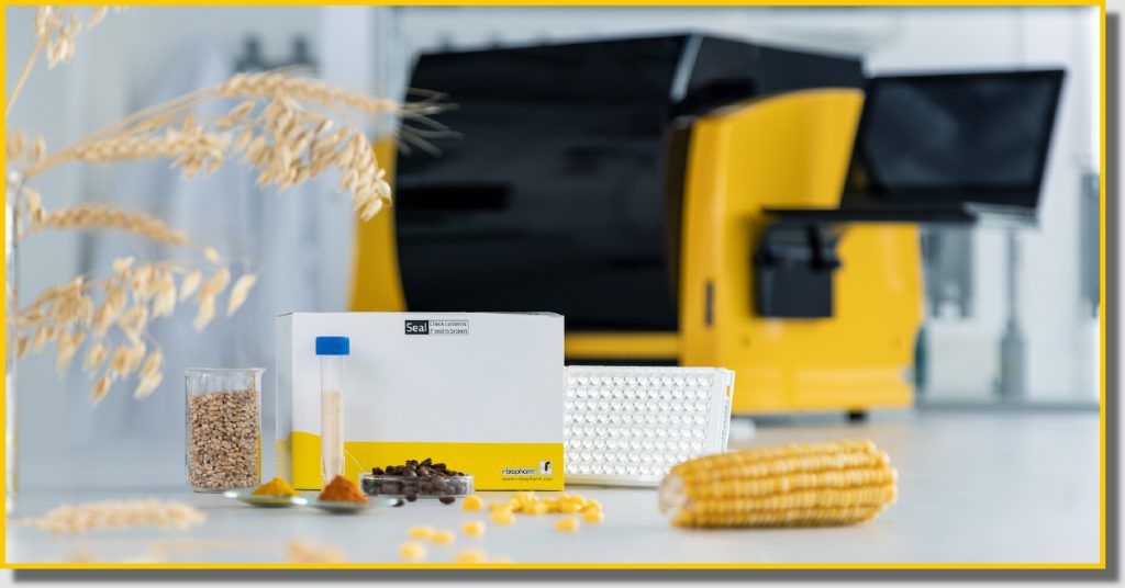 A yellow and black machine surrounded by corn and various agricultural items